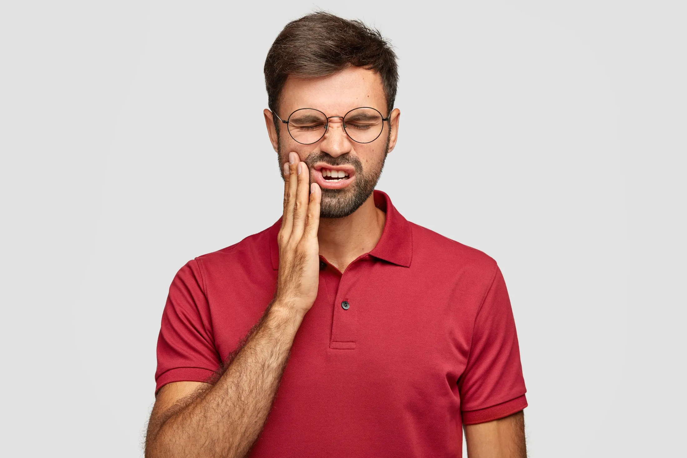 Homem com a mão no rosto, com dor de dente
