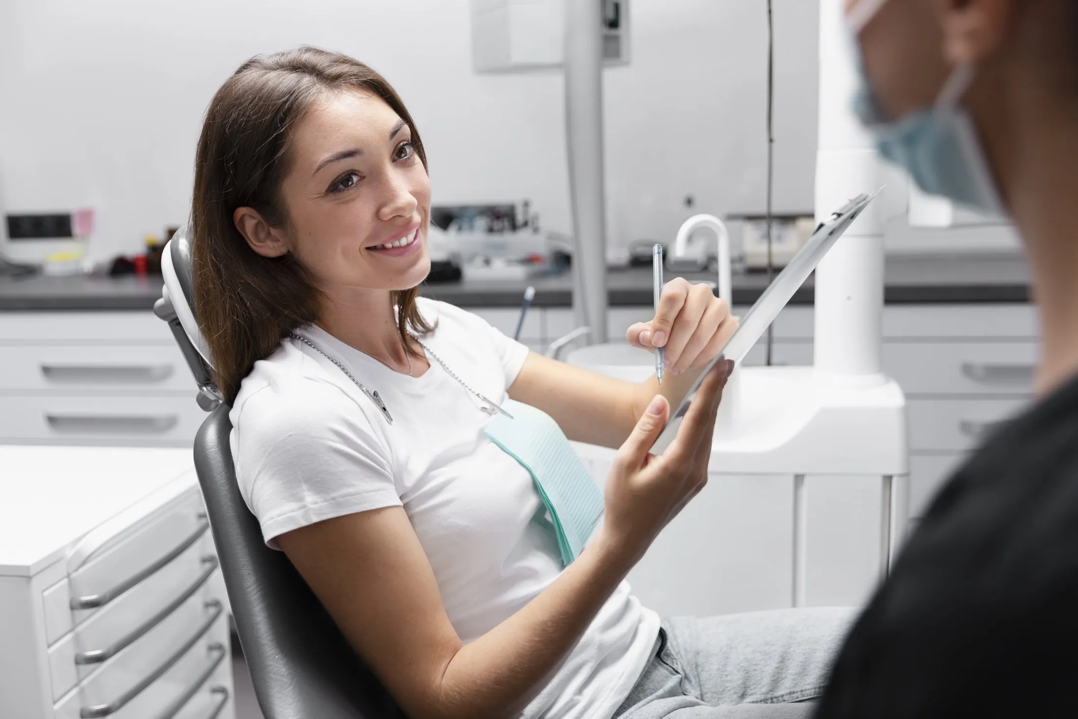 Paciente sorrindo na cadeira do dentista, olhando o resultado no espelho